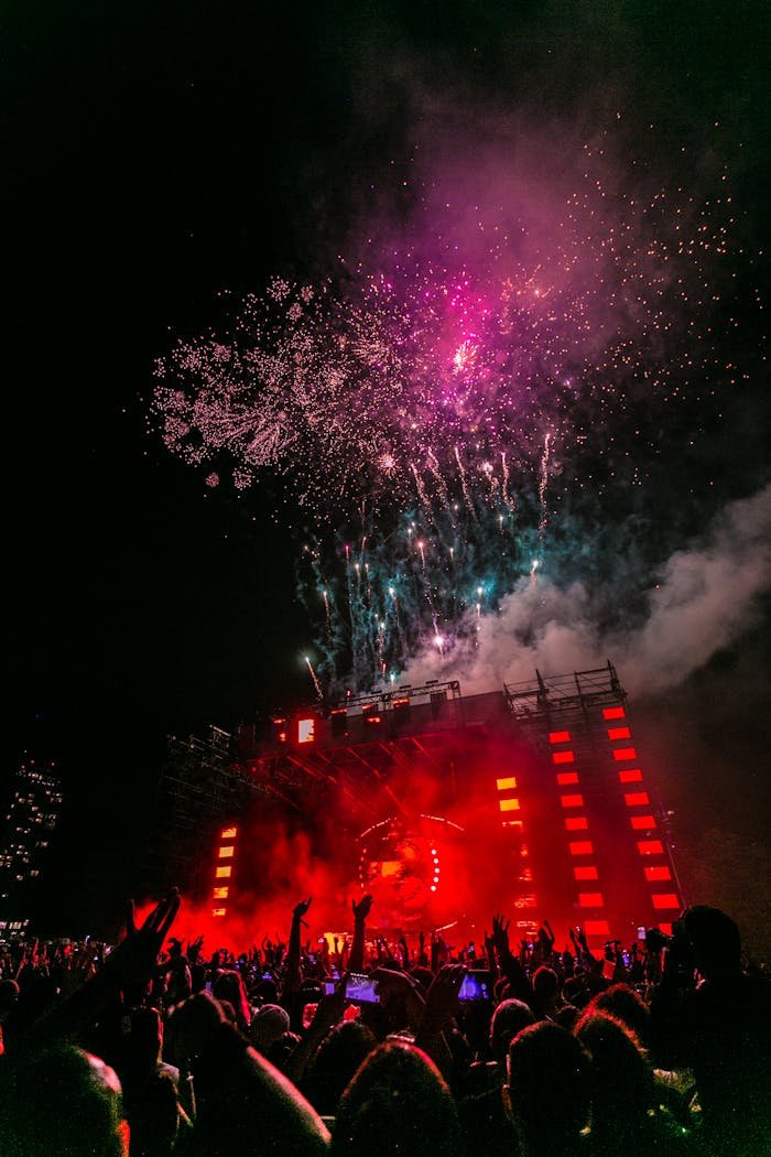 Energetic outdoor concert at night with a vibrant fireworks display and crowd enjoying live music.